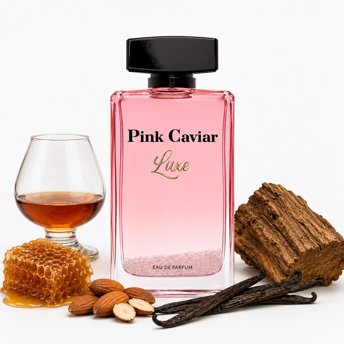 Pink Caviar Luxe Eau de Parfum bottle with a black cap, styled with a cognac glass, honeycomb, almonds, vanilla beans, and a piece of wood on a white background.